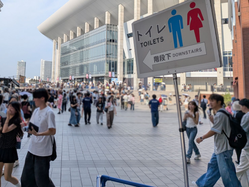多数の来場者が行き交う広場で、トイレの方向を示す案内標識が設置された様子