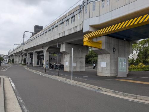 高架下に道路、駐輪場、施設入口が並び、柱にDゾーンの案内が表示された様子