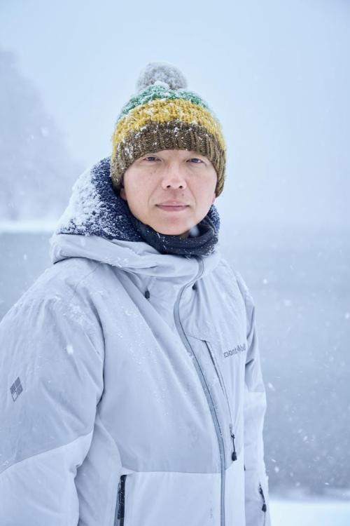 『氷血』メイキング写真　ポンポン付きニット帽をかぶり、雪に包まれている内藤監督