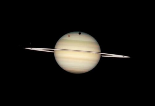 ハッブル宇宙望遠鏡が2009年2月24日に撮影した土星で、4つの衛星が土星の手前を横切っています。