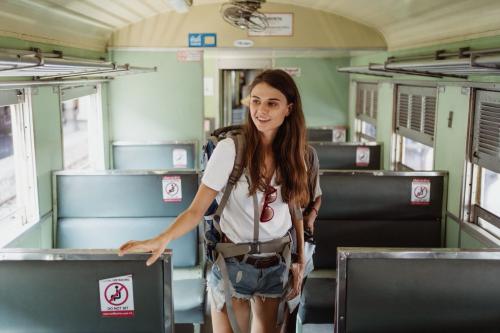 リュックを背負い、列車の車内を歩く女性です。