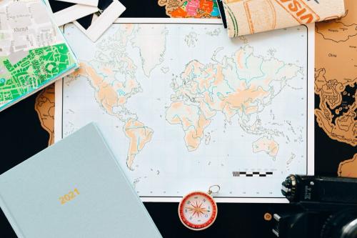 机の上に広げた世界地図です。方位磁針や手帳、ほかの地図も一緒に置かれています。