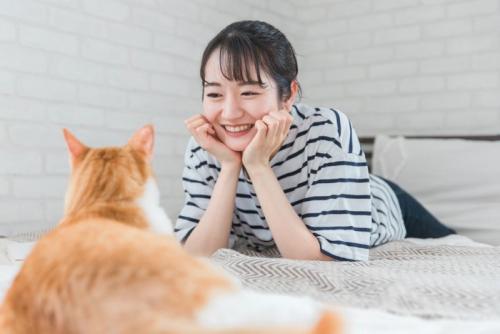 寝そべって猫と見つめ合う女性