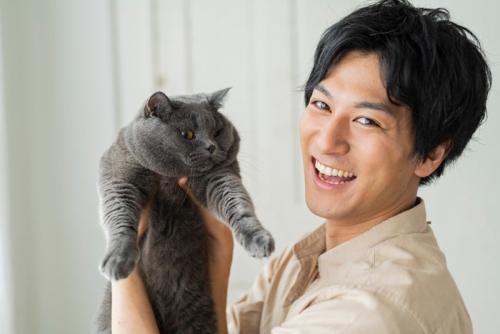 笑顔の男性に持ち上げられている猫