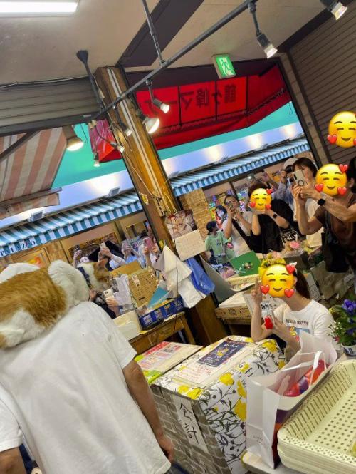 飼い主の肩に乗った猫をカメラで撮影する客たち