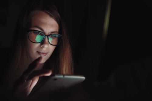 夜更けにスマホの画面を見つめる女性