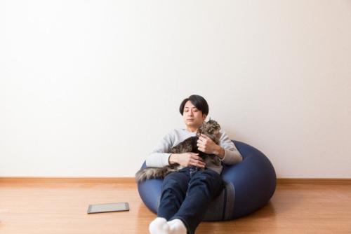 猫を抱いてビーズクッションに座る男性