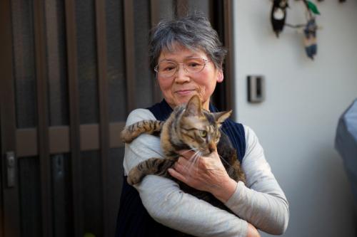 トラ猫を抱くアジア人高齢女性