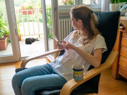 ベランダでくつろぐ黒猫を見る女性