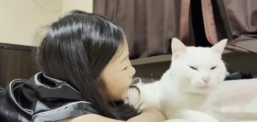 ベッドの上に寝転ぶ子どもと猫