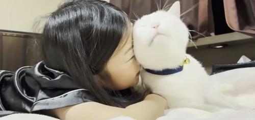 ベッドの上に寝転ぶ子どもと猫