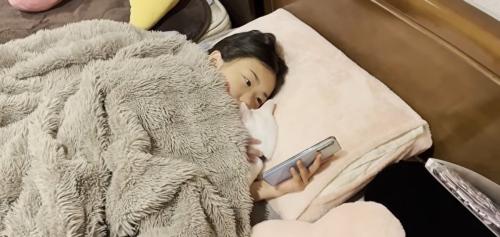 ベッドに寝ている子どもと猫