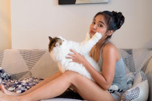 女性の顔に手を突っ張る猫