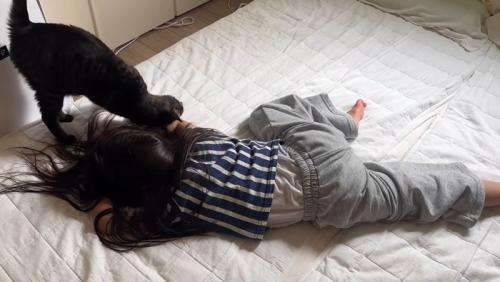倒れる真似をしている女の子と猫