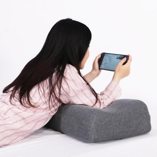 ゲーミングロングピローを使ってうつ伏せで携帯ゲーム機をプレイする様子
