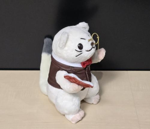 本と片眼鏡を持つログ男ぬいぐるみの横姿