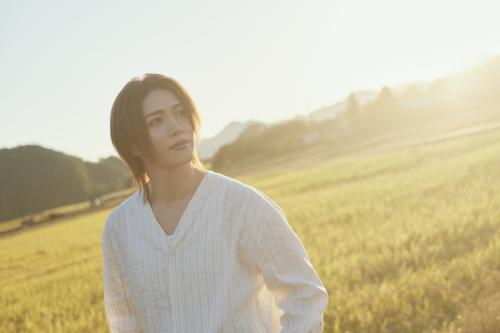夕日の差す草原で白いシャツを着た立石俊樹