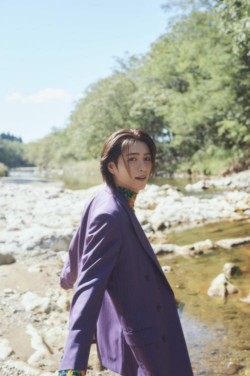 川辺で紫色のスーツ姿を見せる立石俊樹