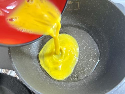 溶き卵をフライパンに入れる