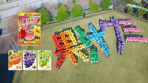 カラフルな「果汁グミ」の文字が校庭に浮かび上がる