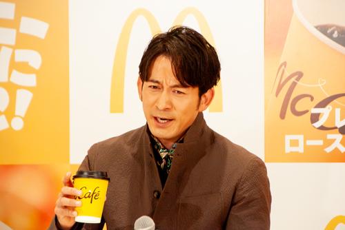 新「プレミアムローストコーヒー」（ホット）を飲み、「コクが一段と深くなっている」と絶賛する岡田准一