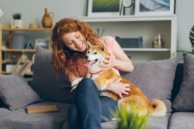 犬を撫でながら顔を覗き込む女性