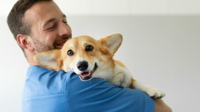 獣医に抱っこされる犬