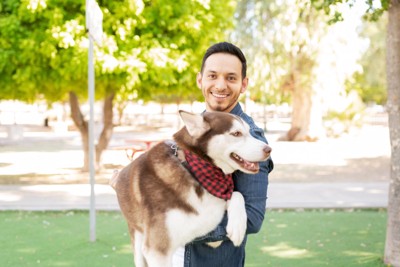 大型犬を抱っこする男性