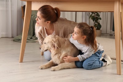 テーブルの下に避難する親子と犬