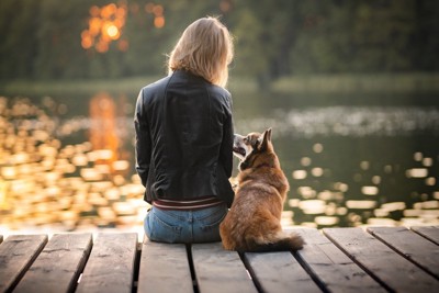 湖を眺めながら会話する犬と女性