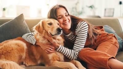 ソファの上で犬と触れ合う女性