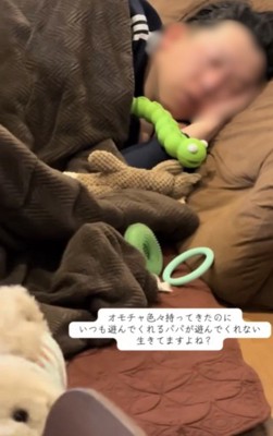 おもちゃに囲まれて寝る人