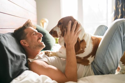 ベッドで寝ている男性と犬