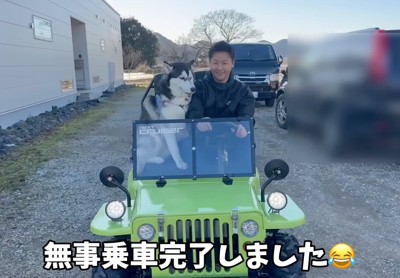 ミニカーに乗るハスキー犬と男性