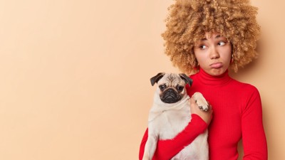 犬を抱っこする不満そうな女性
