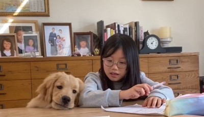 暇そうな顔で女の子にもたれかかる犬