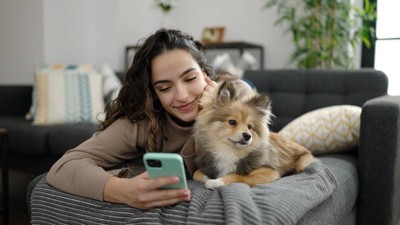 犬とスマホを使う女性