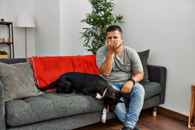 犬の隣で鼻をつまむ男性