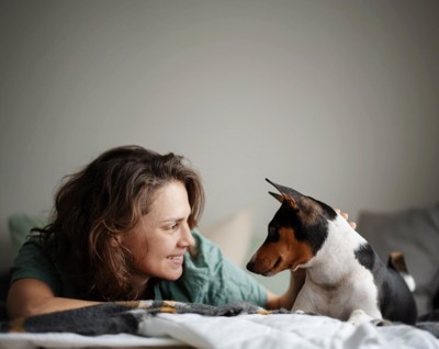 ベッドで見つめ合う女性と犬
