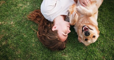 芝生に寝転がる犬と女性