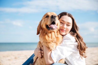 女性にハグされている犬